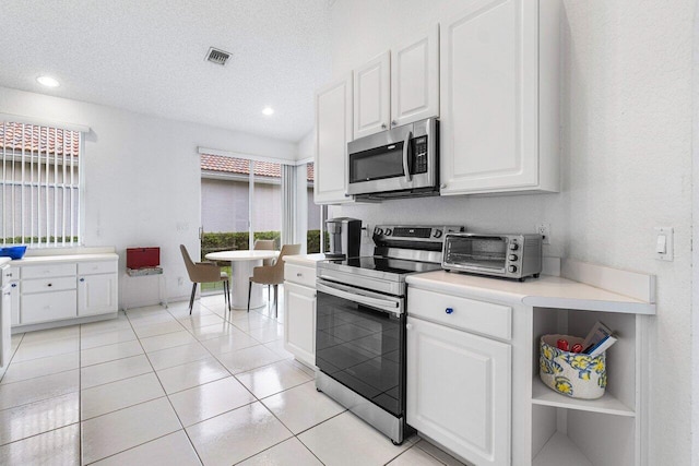 kitchen featuring appliances with stainless steel finishes, white cabinets, a textured ceiling, and light tile patterned floors