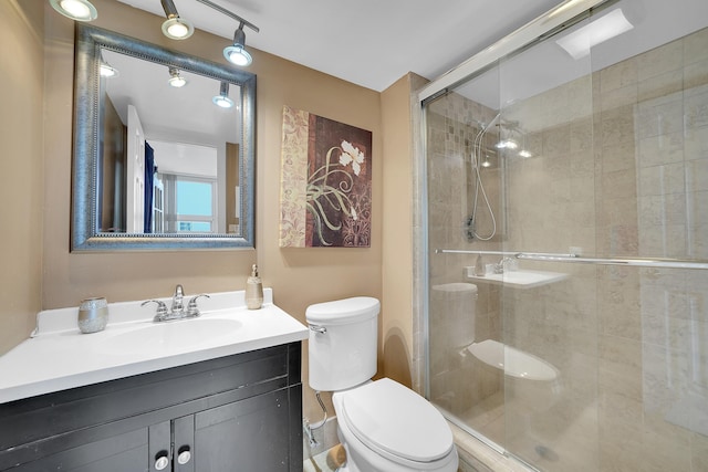 bathroom with an enclosed shower, vanity, and toilet