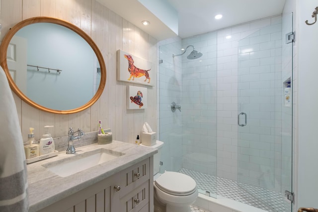 bathroom featuring vanity, an enclosed shower, toilet, and wood walls