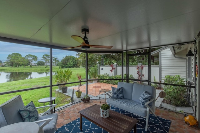 sunroom featuring ceiling fan and a water view