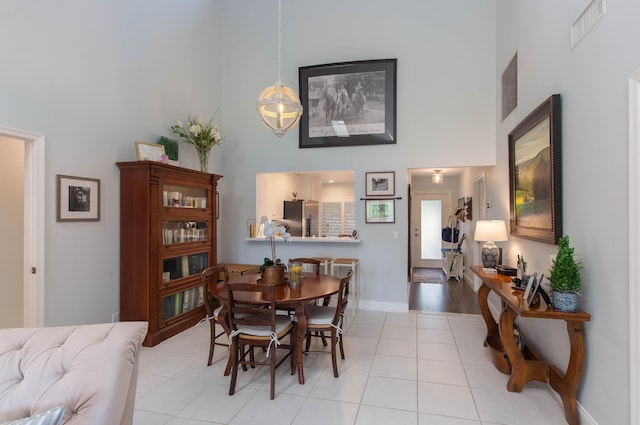 dining space with a towering ceiling and light tile patterned floors