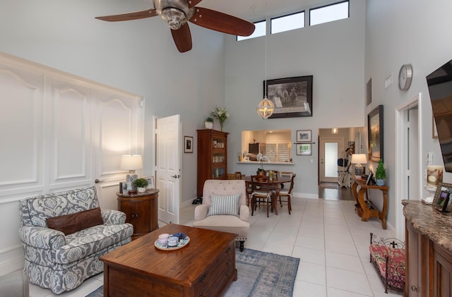 tiled living room with ceiling fan and a high ceiling