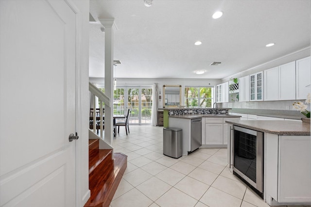 kitchen featuring white cabinetry, light tile patterned floors, a kitchen island, and beverage cooler