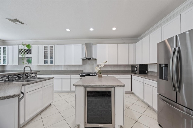 kitchen featuring appliances with stainless steel finishes, white cabinets, a center island, beverage cooler, and wall chimney exhaust hood