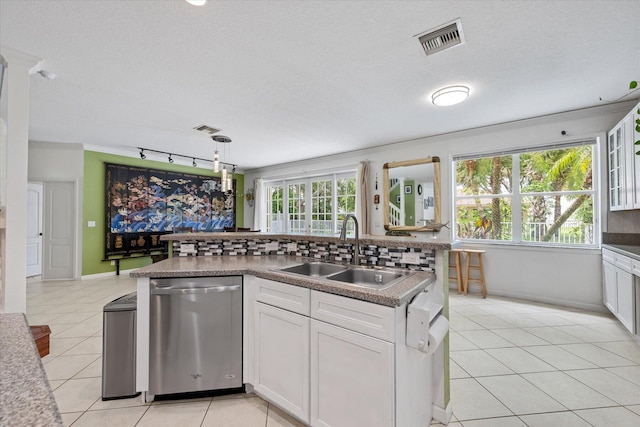 kitchen with light tile patterned flooring, white cabinetry, stainless steel dishwasher, decorative backsplash, and sink