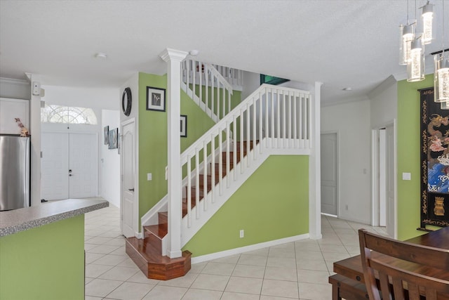 staircase featuring a textured ceiling, ornamental molding, and light tile patterned floors