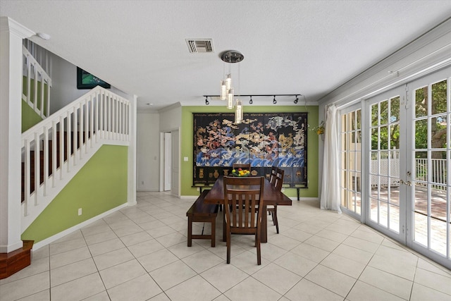 tiled dining room with ornamental molding, a textured ceiling, rail lighting, and french doors