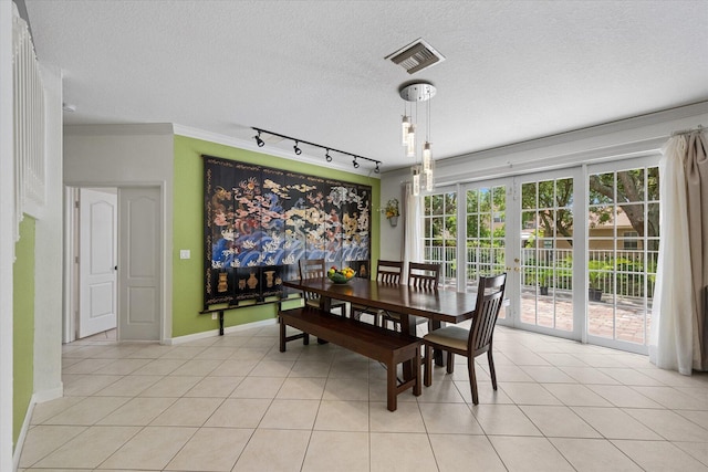 dining room featuring track lighting, crown molding, light tile patterned floors, and a textured ceiling