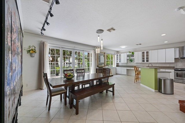 tiled dining area with track lighting and a textured ceiling