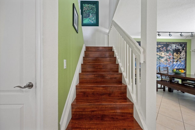 staircase with rail lighting and tile patterned flooring