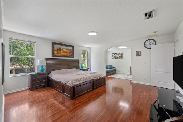 bedroom featuring a textured ceiling, multiple windows, and wood-type flooring