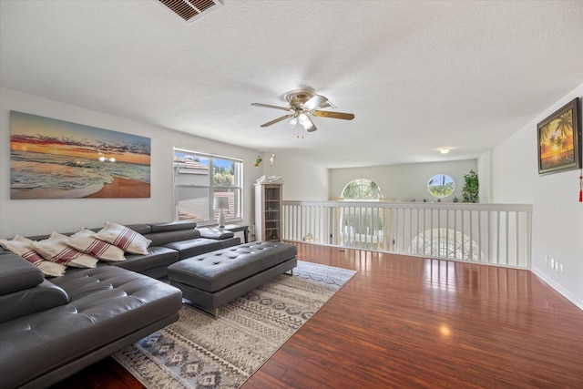 living room with a textured ceiling, ceiling fan, and wood-type flooring