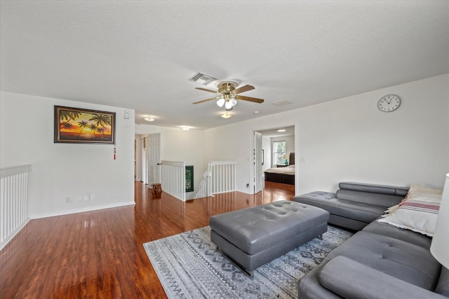 living room featuring ceiling fan, a textured ceiling, and hardwood / wood-style flooring