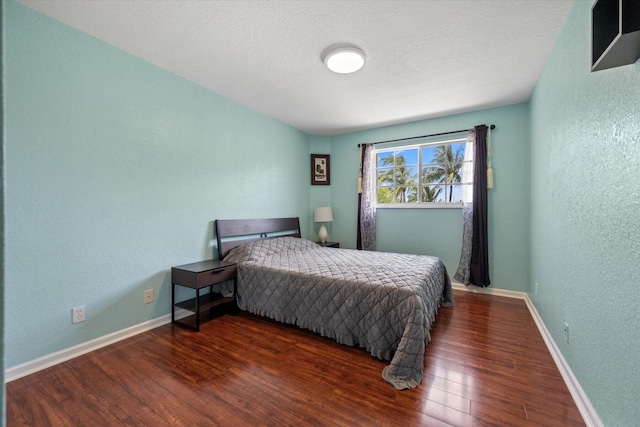 bedroom with dark hardwood / wood-style flooring and a textured ceiling