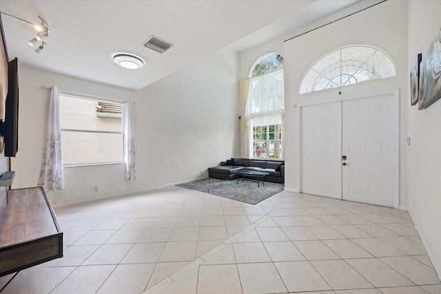 entryway with a textured ceiling, light tile patterned floors, and track lighting