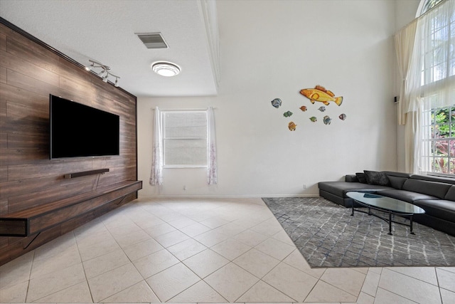 tiled living room with wood walls, rail lighting, and a textured ceiling