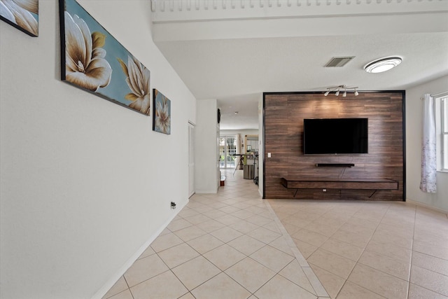 unfurnished living room featuring light tile patterned flooring, a textured ceiling, plenty of natural light, and track lighting