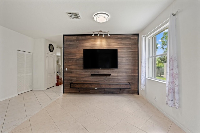 unfurnished living room with rail lighting and light tile patterned floors