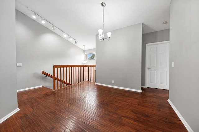 spare room featuring dark hardwood / wood-style floors and an inviting chandelier