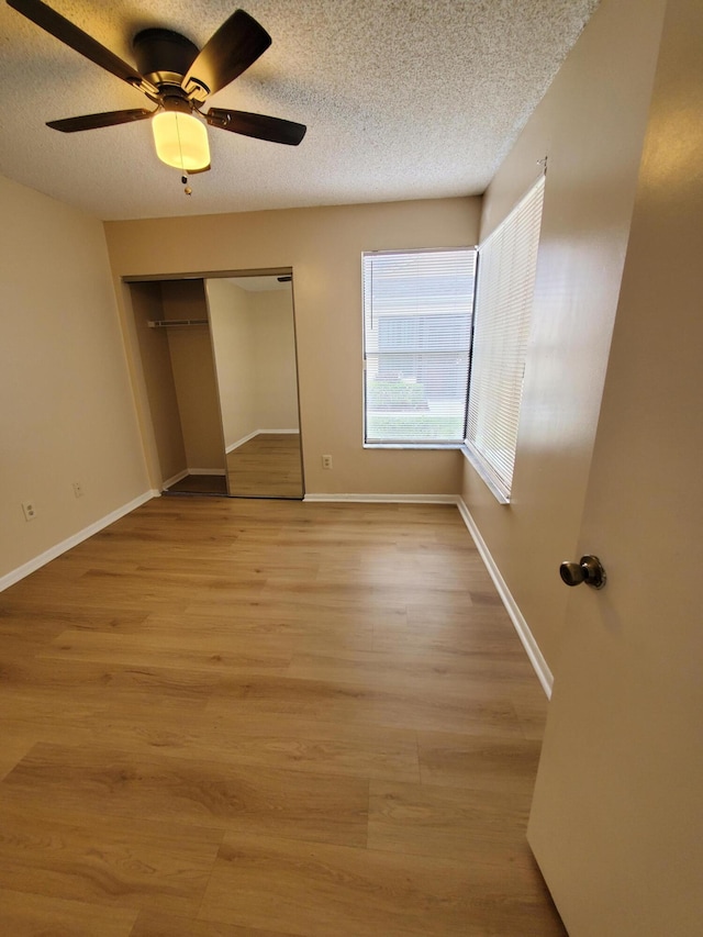 unfurnished bedroom featuring ceiling fan, light hardwood / wood-style floors, a textured ceiling, and a closet