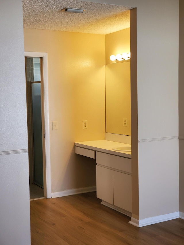 bathroom with a textured ceiling, hardwood / wood-style floors, and vanity