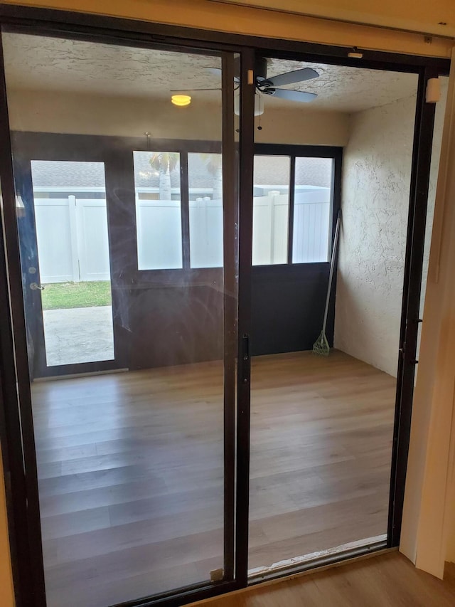 doorway with ceiling fan, a wealth of natural light, and hardwood / wood-style floors