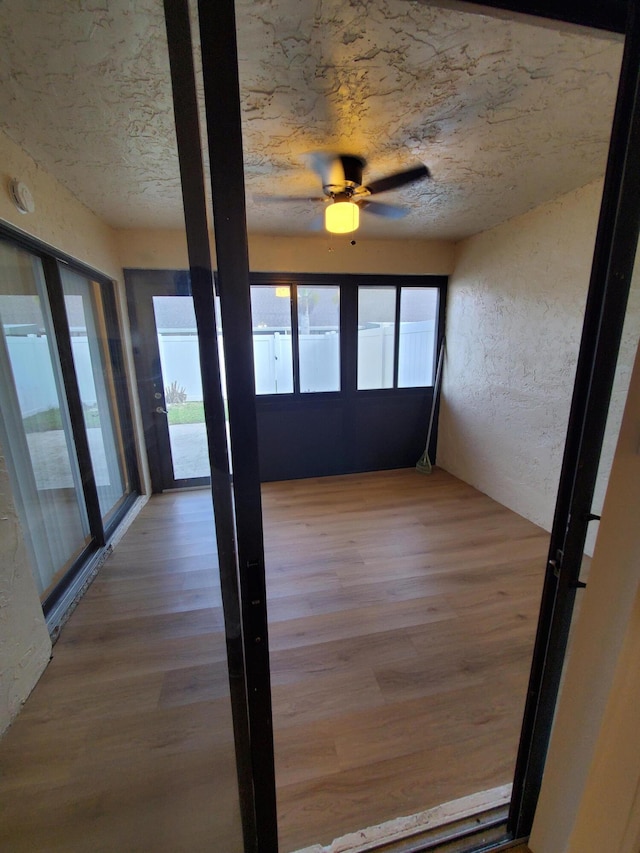 unfurnished sunroom with ceiling fan