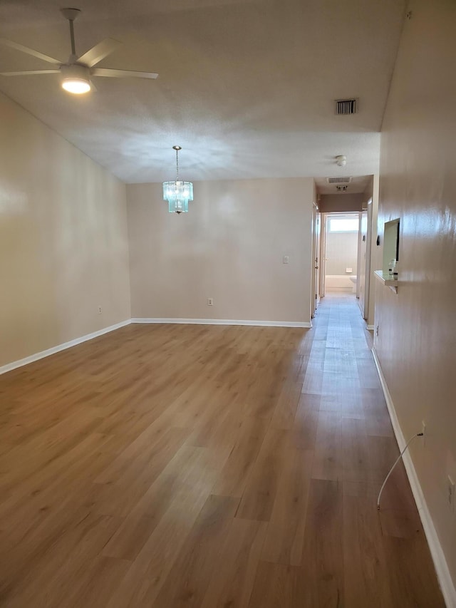 interior space with ceiling fan with notable chandelier and wood-type flooring