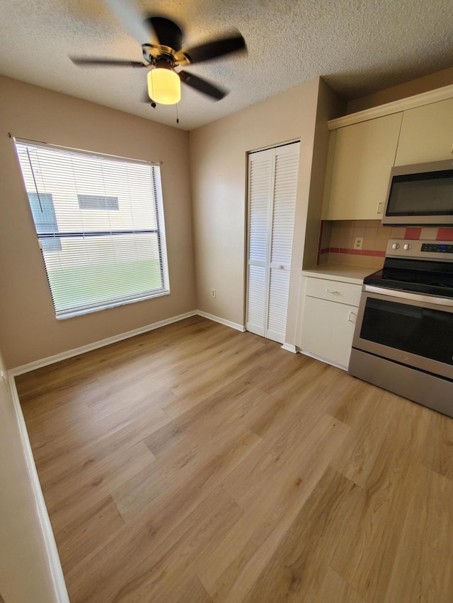 kitchen with light wood-type flooring, ceiling fan, appliances with stainless steel finishes, and plenty of natural light