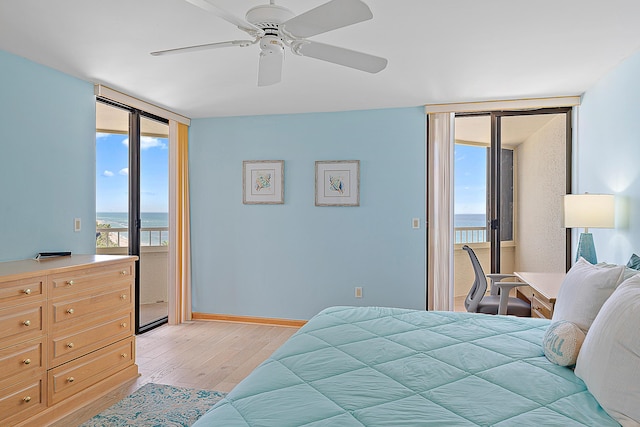 bedroom featuring ceiling fan, access to outside, expansive windows, light wood-type flooring, and a water view