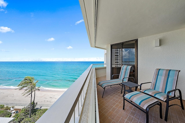 balcony with a water view and a view of the beach