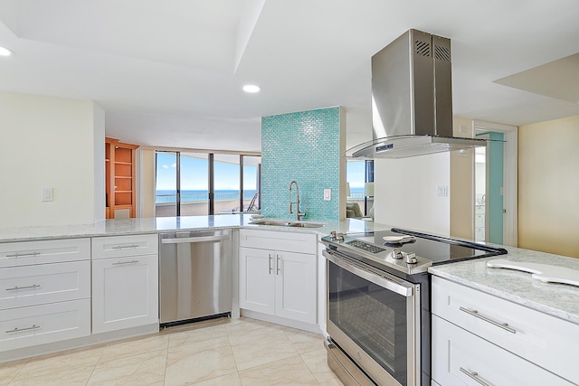 kitchen with island range hood, stainless steel appliances, light stone countertops, white cabinets, and sink