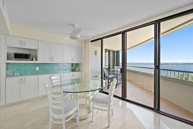 dining area with ceiling fan, a water view, and light tile patterned flooring