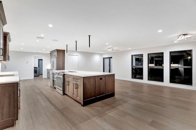 kitchen with a center island, stainless steel appliances, light wood-type flooring, and sink