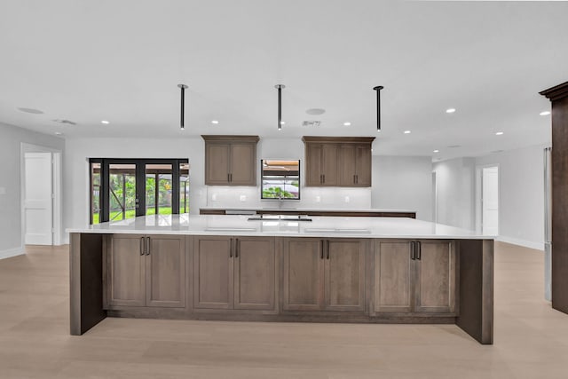 kitchen with french doors, a large island, backsplash, and light hardwood / wood-style flooring