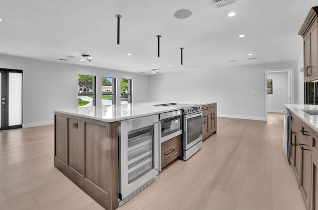 kitchen featuring stainless steel electric range oven, a kitchen island, wine cooler, light hardwood / wood-style floors, and french doors