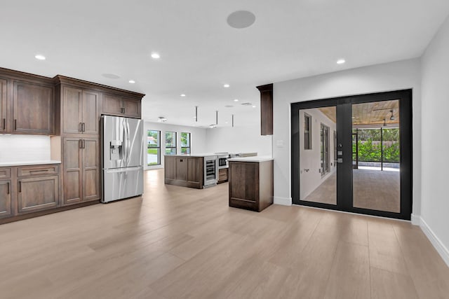 kitchen featuring light hardwood / wood-style flooring, a center island, dark brown cabinetry, and stainless steel refrigerator with ice dispenser