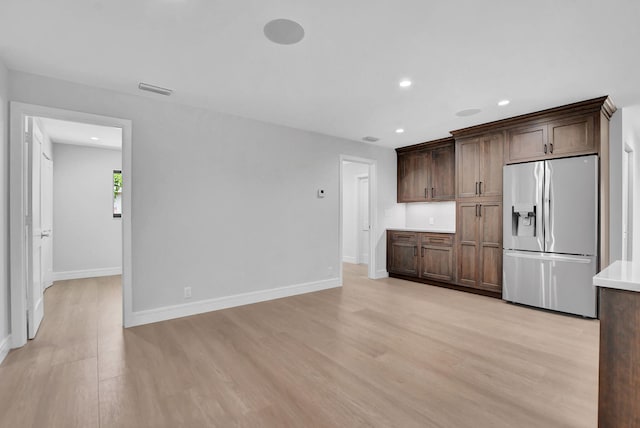 kitchen featuring dark brown cabinets, stainless steel fridge, and light hardwood / wood-style floors