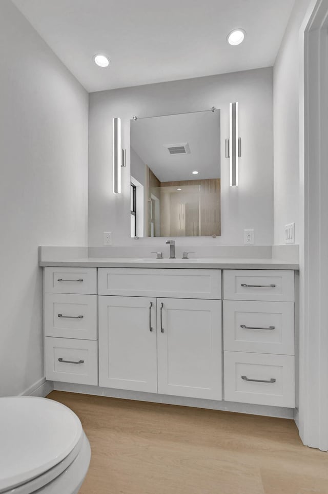 bathroom featuring vanity, toilet, and hardwood / wood-style floors