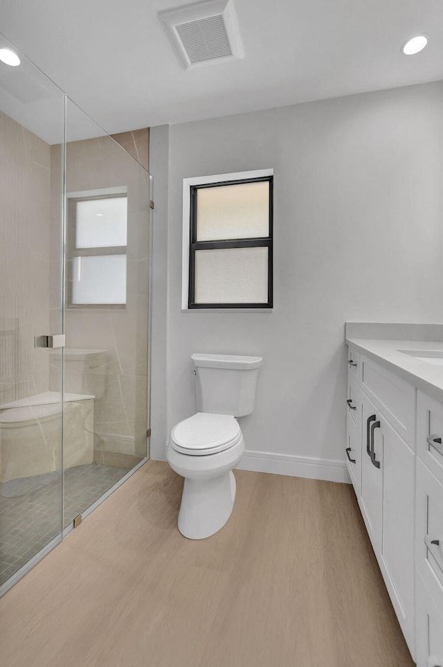 bathroom with toilet, hardwood / wood-style flooring, walk in shower, and vanity