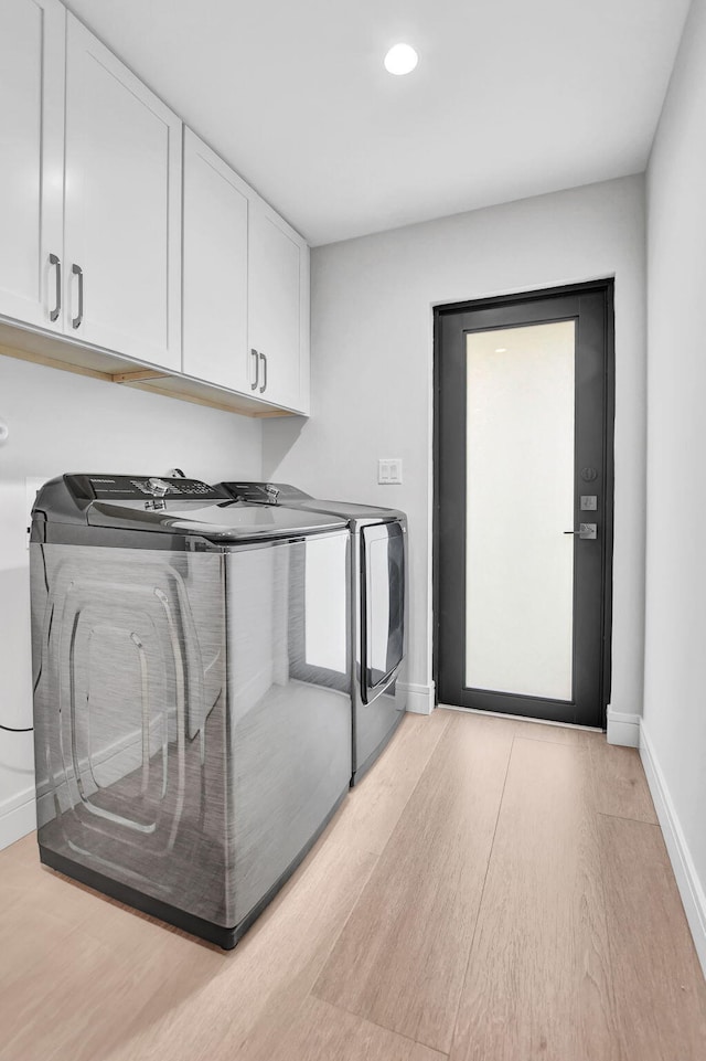 laundry area featuring washer and clothes dryer, cabinets, and light hardwood / wood-style floors