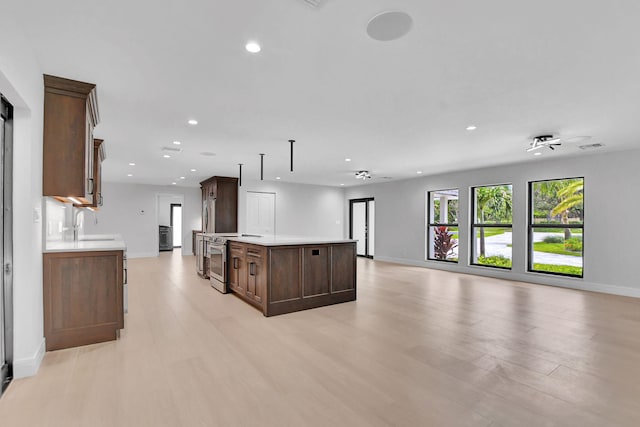 kitchen with stainless steel range with electric stovetop, light hardwood / wood-style floors, pendant lighting, a kitchen island, and sink