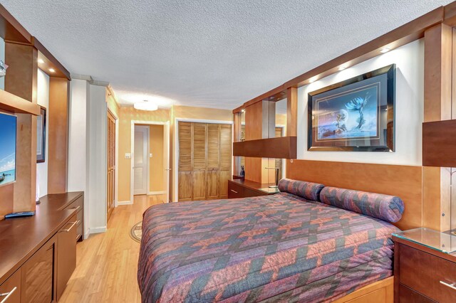 bedroom featuring multiple windows, a textured ceiling, and light wood-type flooring