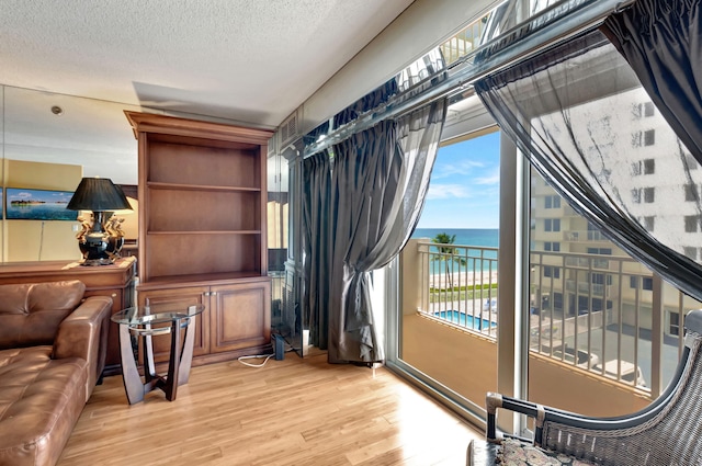 interior space with a water view, a textured ceiling, and light hardwood / wood-style floors