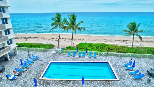 view of swimming pool featuring a water view and a beach view