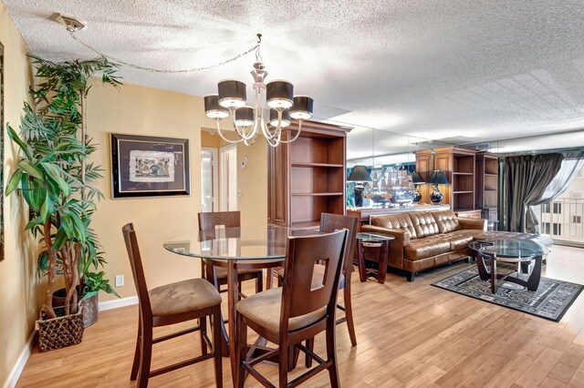 dining area featuring light hardwood / wood-style flooring, a chandelier, and a textured ceiling