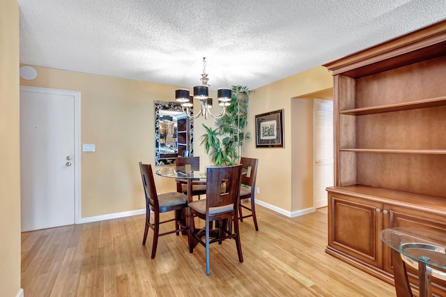 dining area with light hardwood / wood-style floors, a notable chandelier, and a textured ceiling