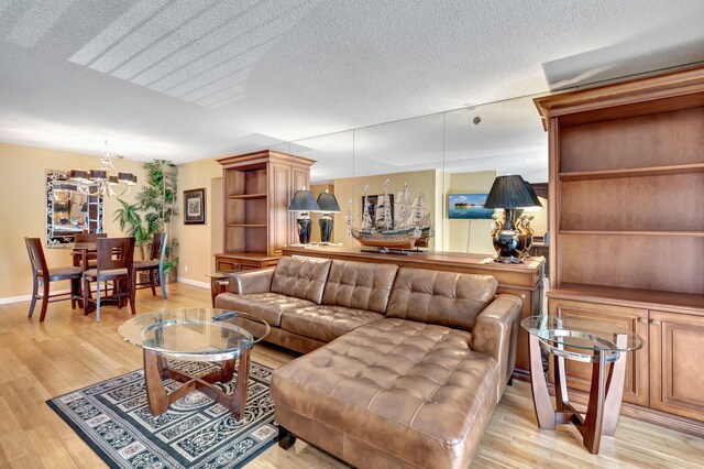 living room with light wood-type flooring, a notable chandelier, and a textured ceiling