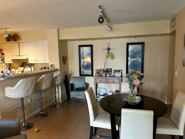 tiled dining area featuring a textured ceiling and rail lighting