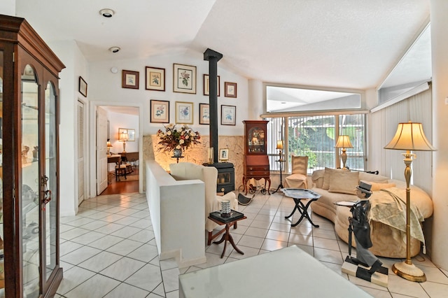 living room featuring a wood stove, a textured ceiling, light tile patterned floors, and vaulted ceiling